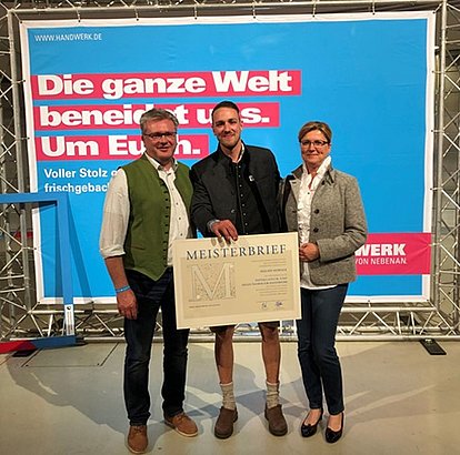 Familie Horner steht vor einem Banner das für eine Ausbildung im Handwerk wirbt.